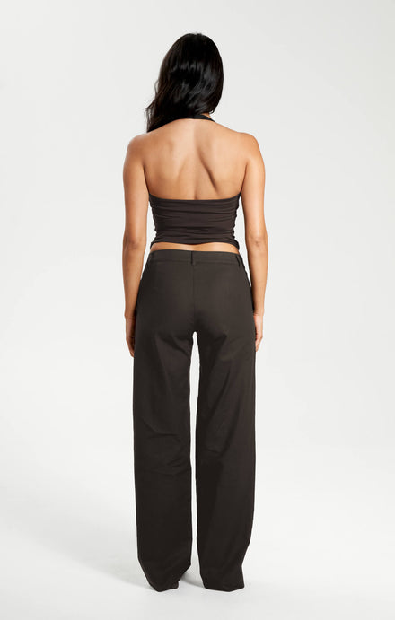 Woman wearing a brown strapless top and black pants on a white background