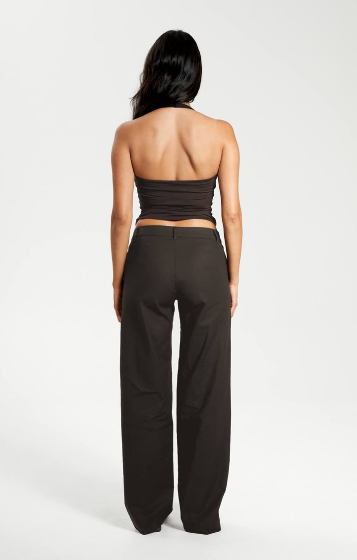 Woman wearing a brown strapless top and black pants on a white background